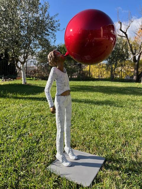 Sculpture contemporaine de Marie-Noëlle Ronayette représentant un personnage soufflant une bulle rouge géante, exposée en extérieur.