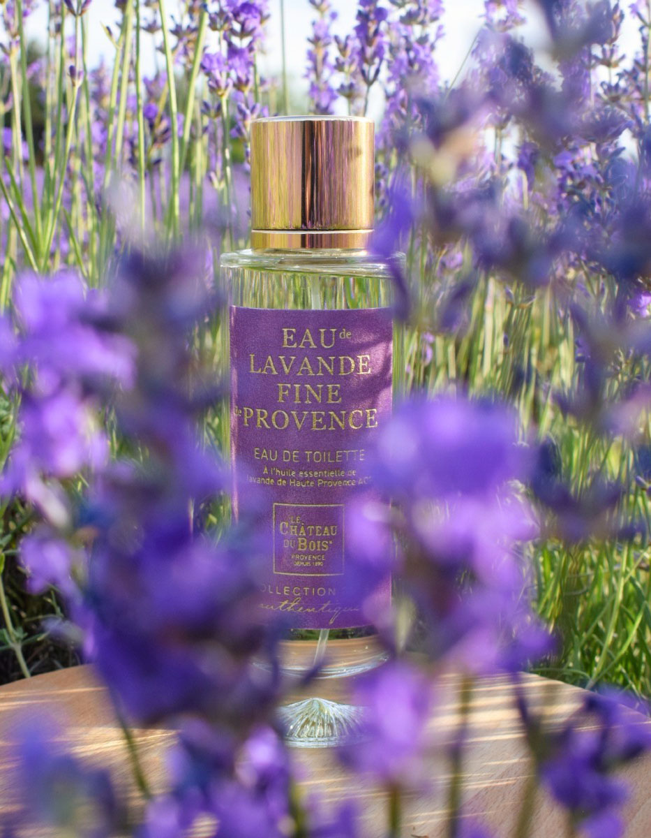 Flacon d’eau de toilette à la lavande fine du Château du Bois dans un champ de lavande en fleurs