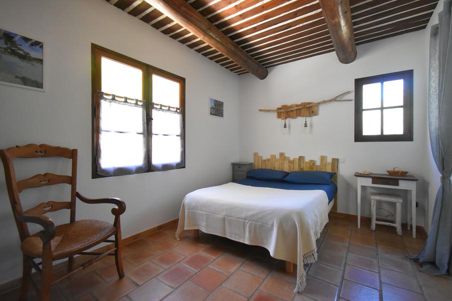 Chambre Luberon avec lit double, poutres apparentes et ambiance provençale