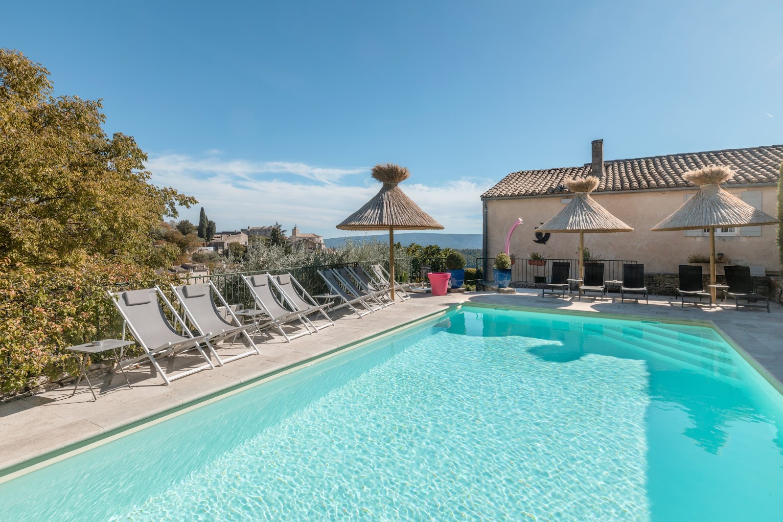 Piscine extérieure de l’hôtel Le Mas des Romarins à Gordes avec transats et vue dégagée sur le Luberon