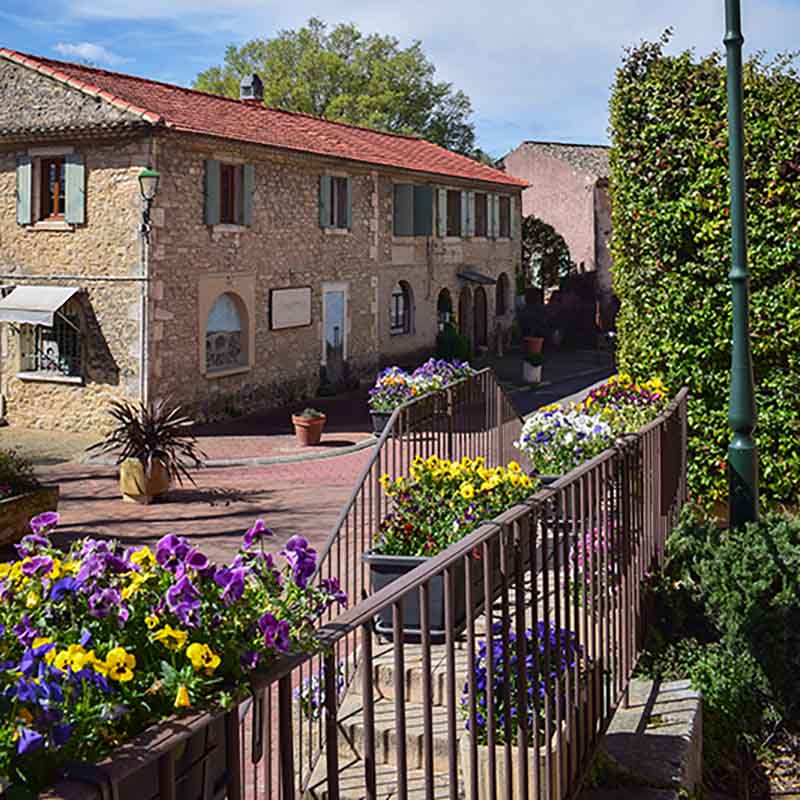 Maisons en pierre et chemin fleuri au cœur du village des Beaumettes, dans le Luberon