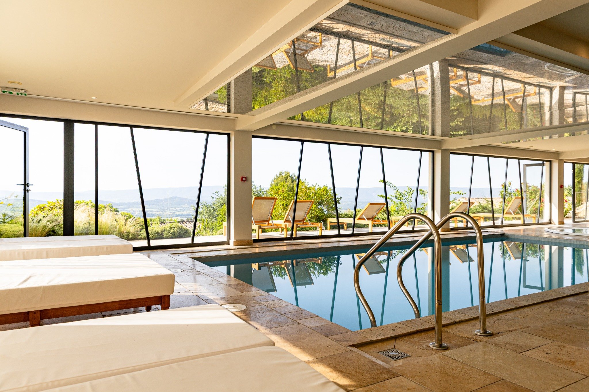 Piscine intérieure du spa du Mas des Herbes Blanches avec vue sur les paysages du Luberon