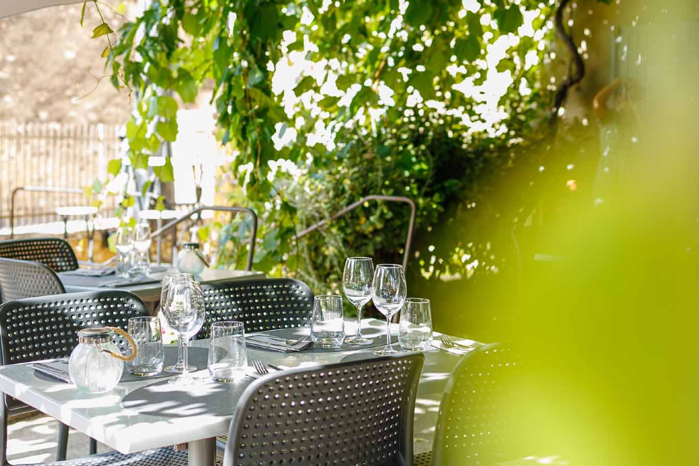 Ambiance conviviale en terrasse au Bistrot des Roques dans le Luberon Table dressée en terrasse sous la vigne au Bistrot des Roques à Saint-Pantaléon