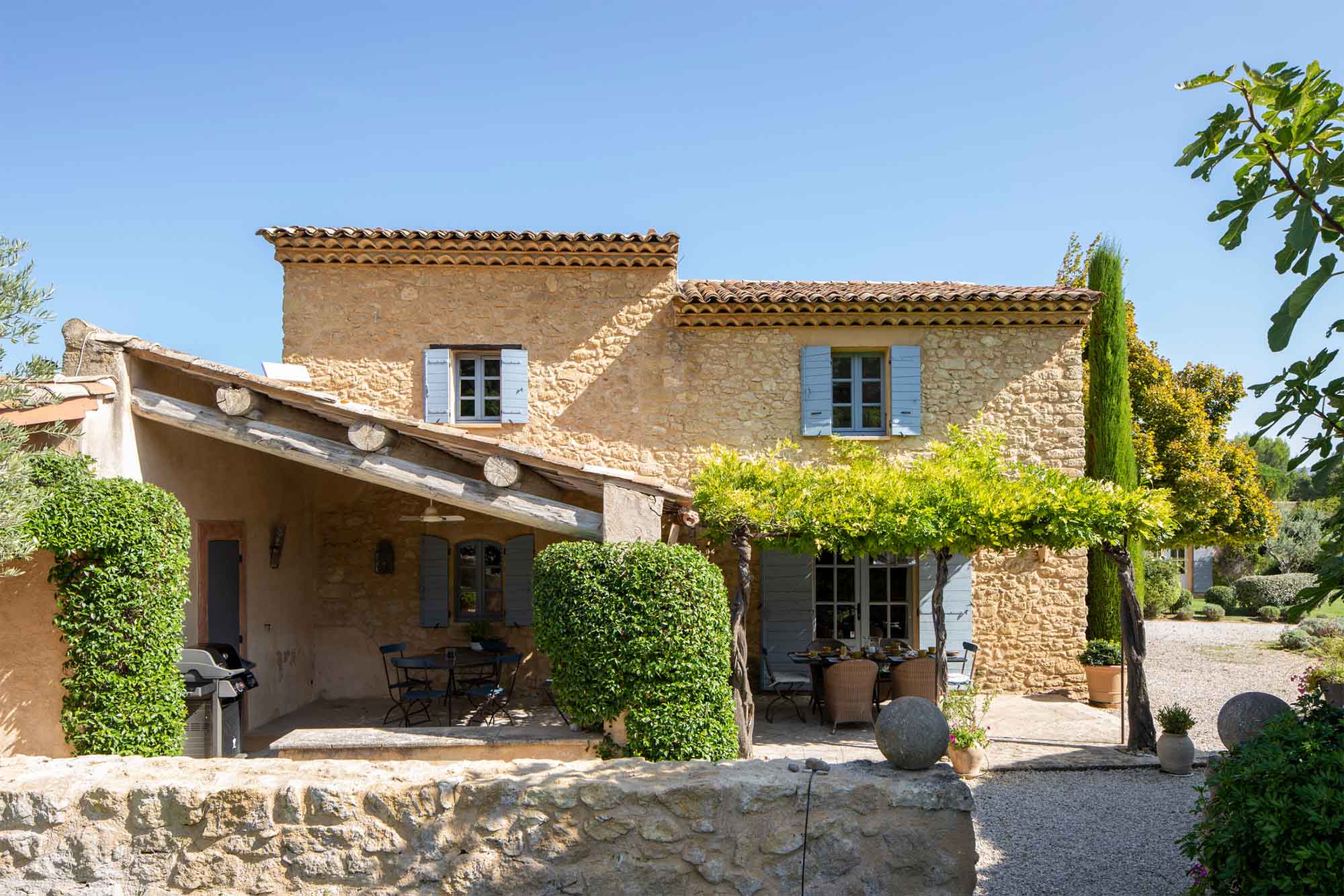 Mas Petit Collongue à Lourmarin - façade du mas provençal et terrasse ombragée Façade en pierre du Mas Petit Collongue à Lourmarin avec terrasse ombragée et jardin