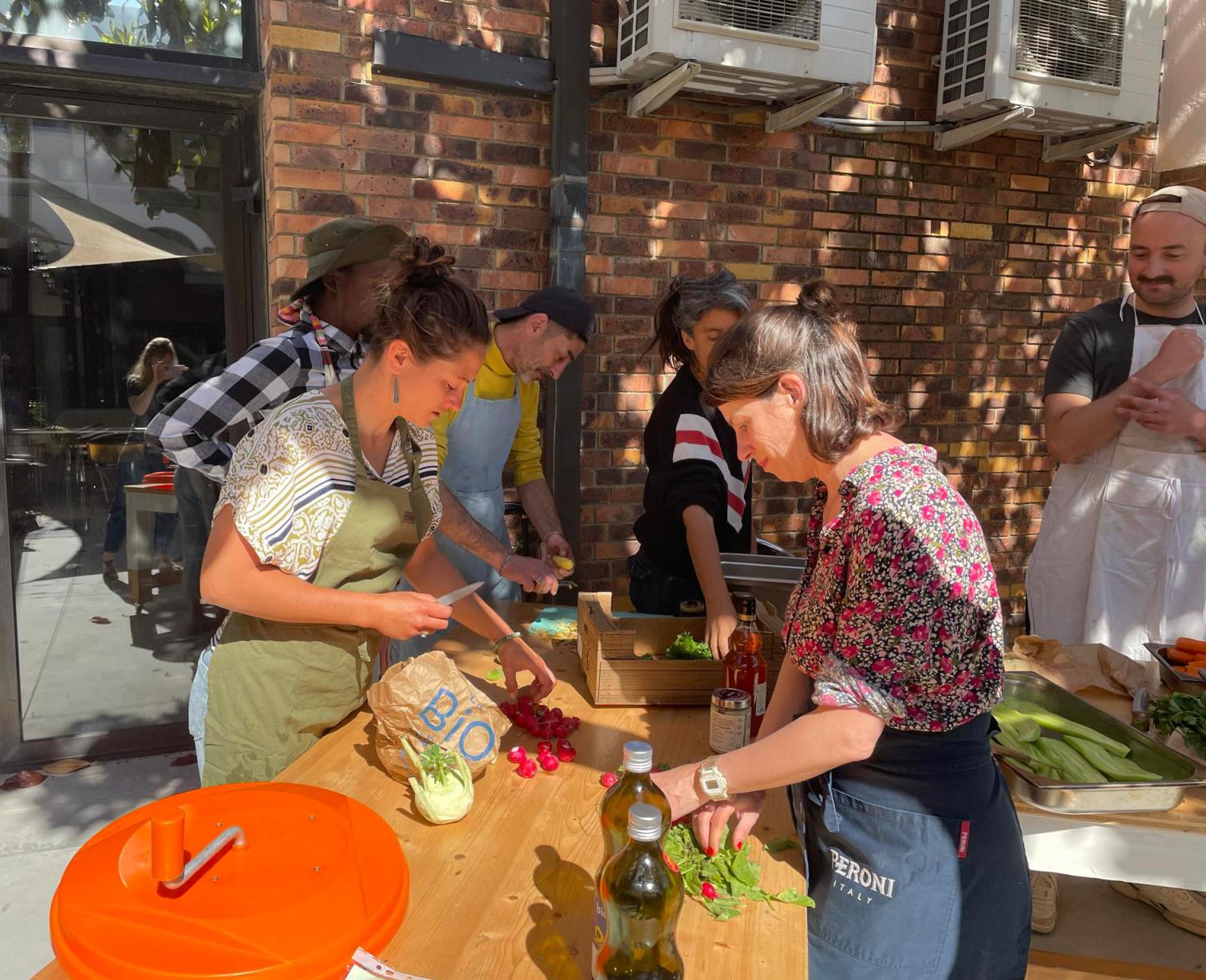 Participants préparant des légumes et cuisinant ensemble lors d’un atelier de cuisine participatif au Festival Confit !