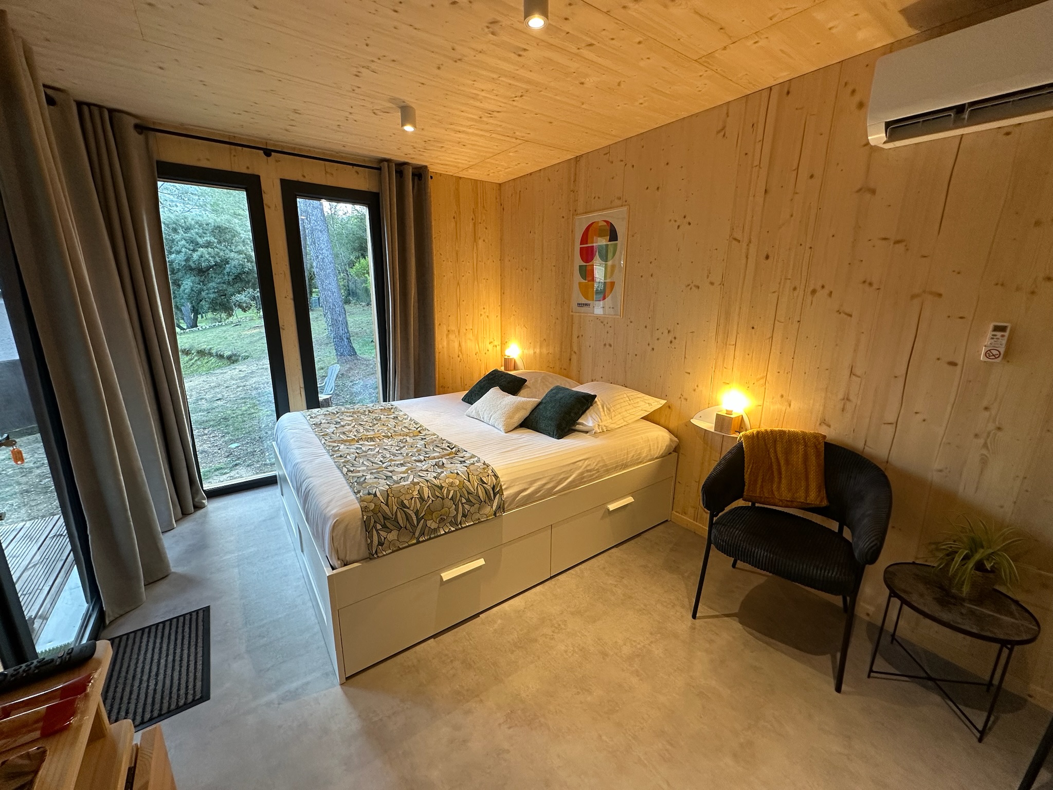 Lit double de la cabane Bird in Provence avec décoration végétale et vue sur le jardin