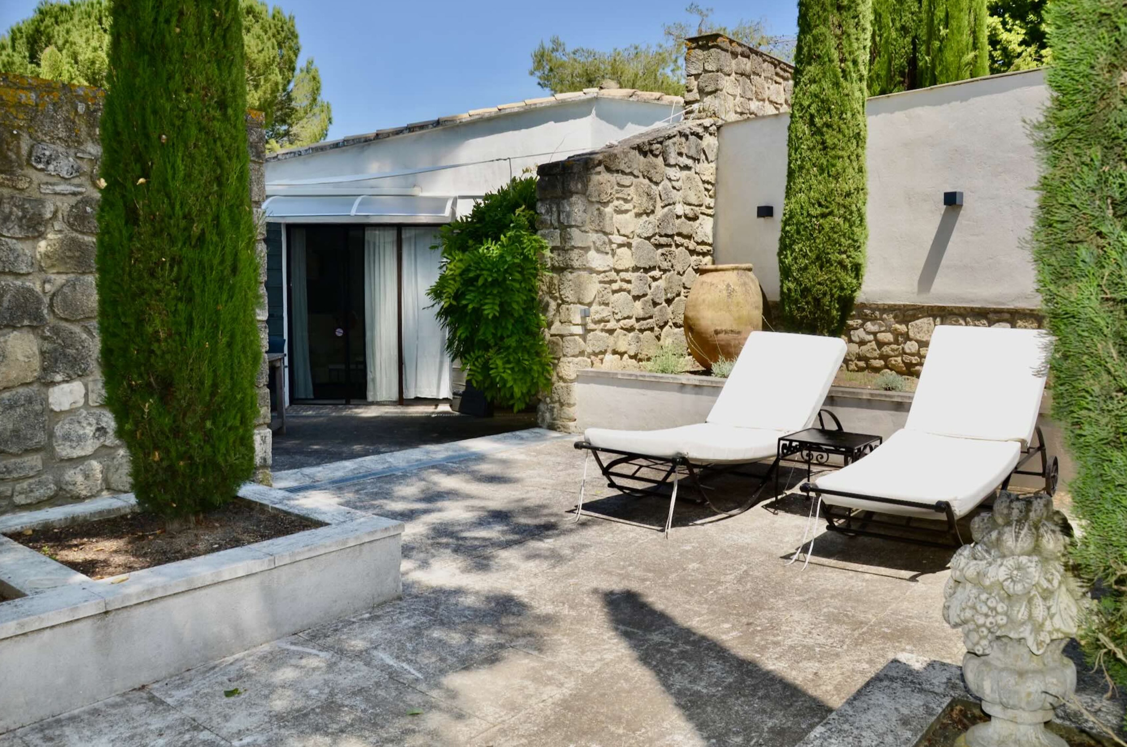 Espace détente extérieur avec bains de soleil, maison Les Oliviers à Oppède Espace détente extérieur avec bains de soleil et cyprès dans le jardin de la maison Les Oliviers à Oppède, en Luberon