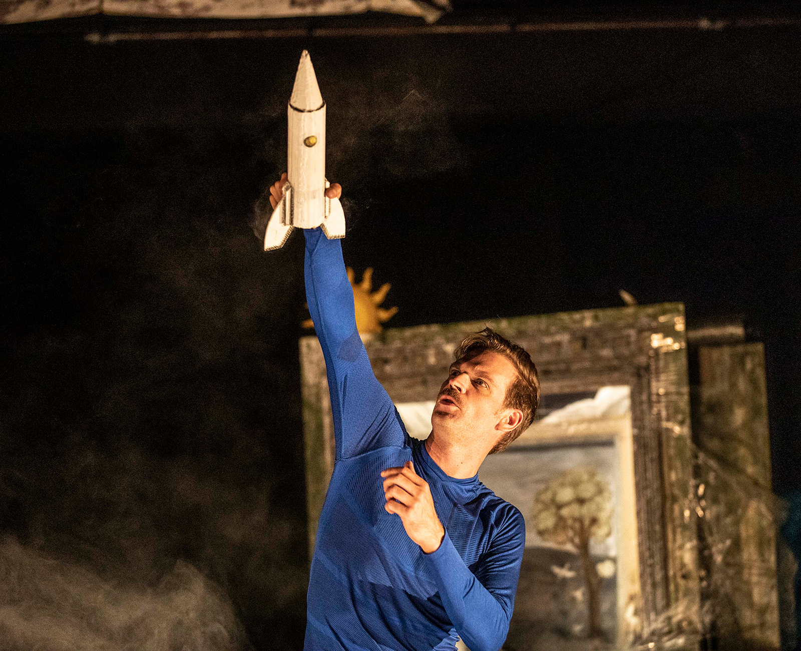 Un interprète du spectacle Fusées tenant une fusée miniature au-dessus de lui