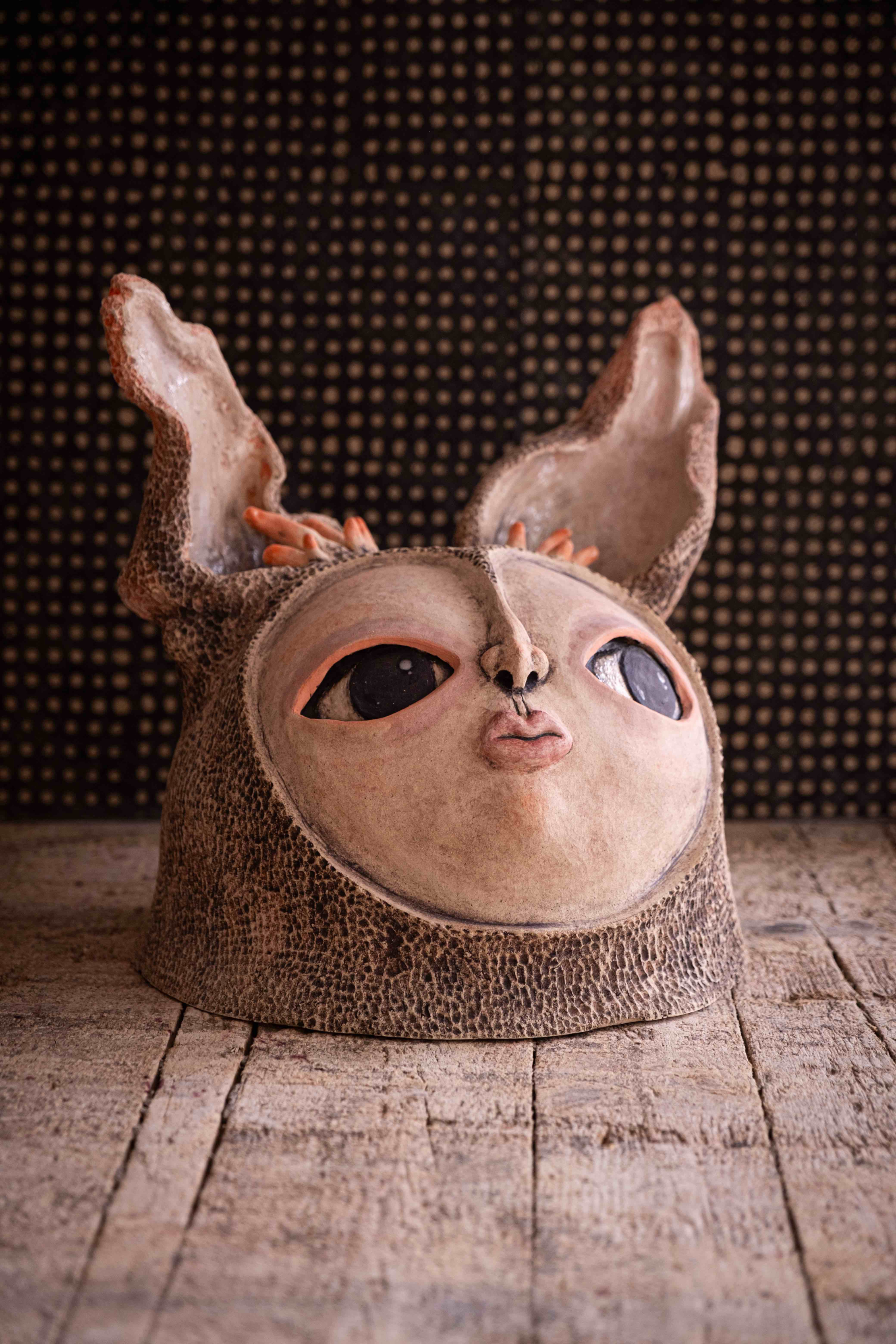 Sculpture de visage en céramique avec de grandes oreilles et des yeux sombres