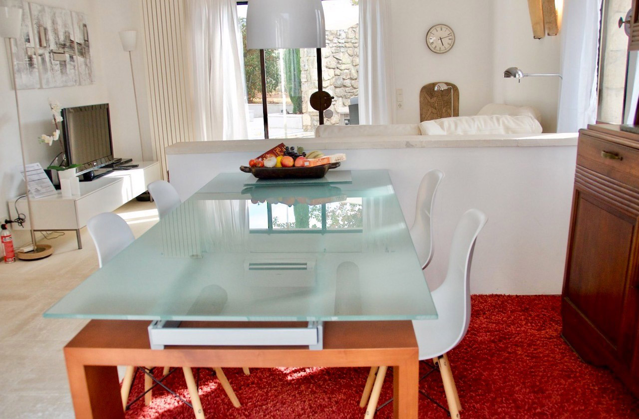 Salle à manger design avec accès terrasse – maison Les Oliviers en Luberon Salle à manger moderne avec table en verre et accès direct à la terrasse et au jardin dans la maison Les Oliviers à Oppède