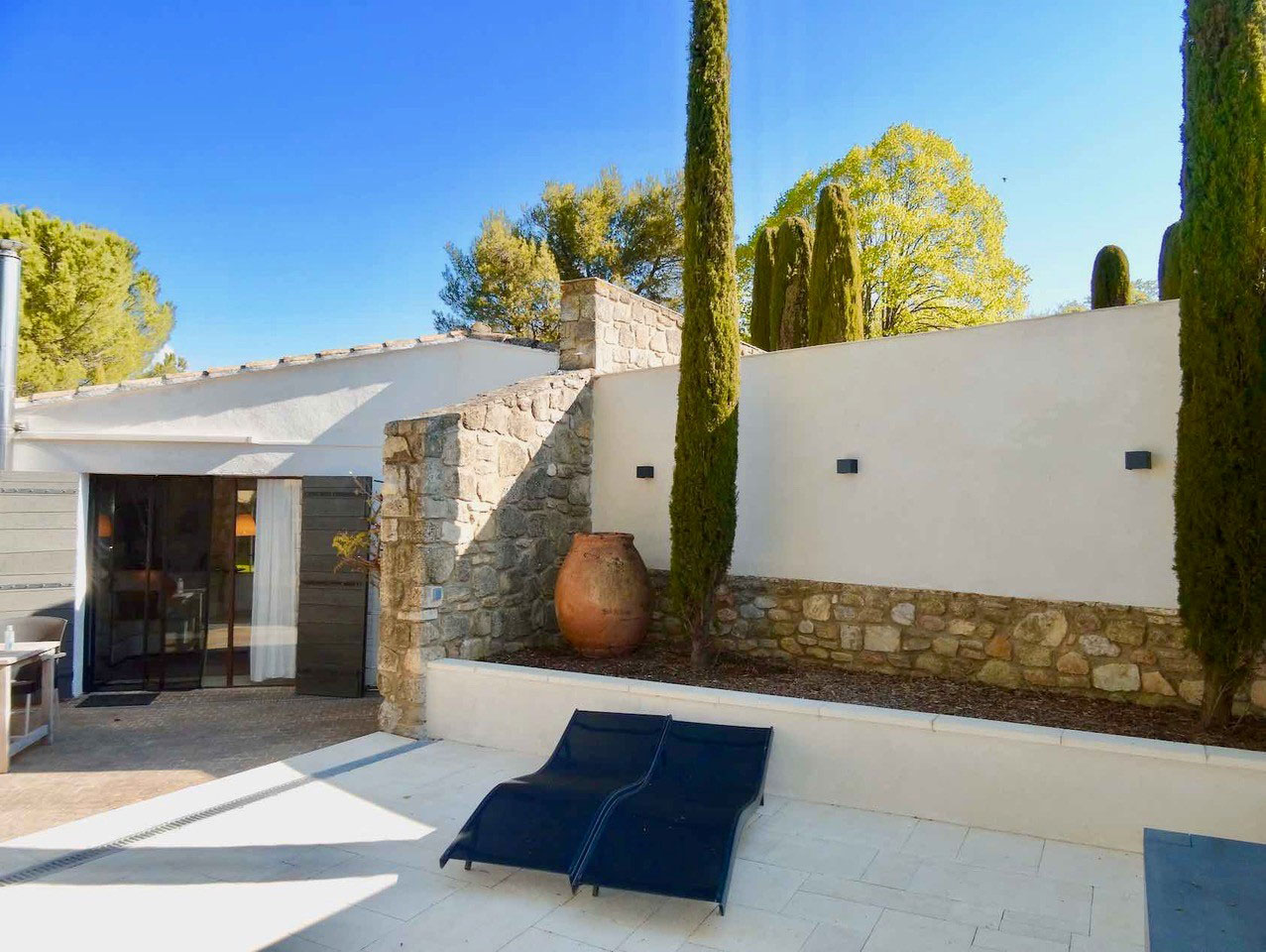 Terrasse privative et architecture provençale, maison Les Oliviers à Oppède Terrasse privative de la maison Les Oliviers à Oppède, avec murs en pierre, cyprès et espaces de détente, dans un cadre paisible du Luberon