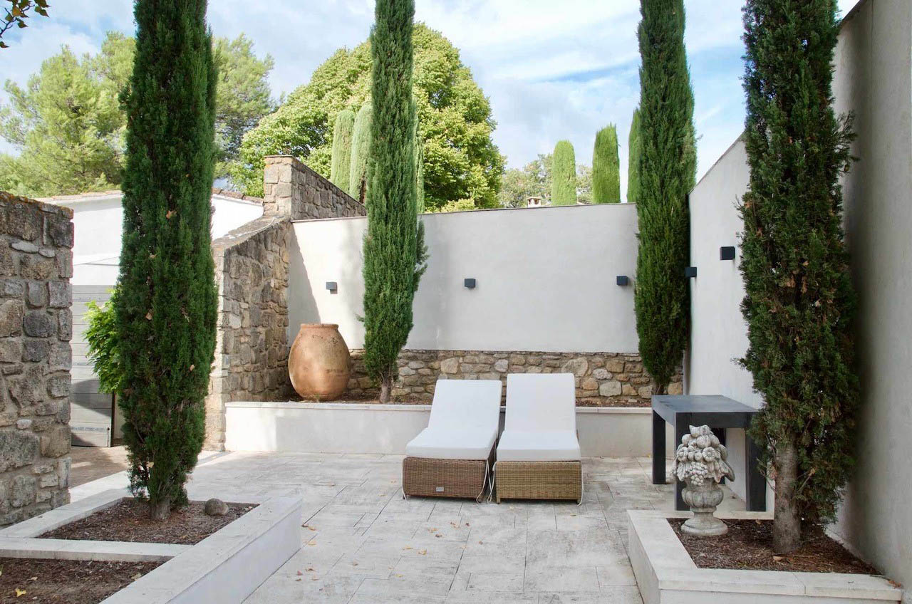 Espace détente extérieur avec bains de soleil, maison Les Oliviers à Oppède Espace détente extérieur avec bains de soleil et cyprès dans le jardin de la maison Les Oliviers à Oppède, en Luberon