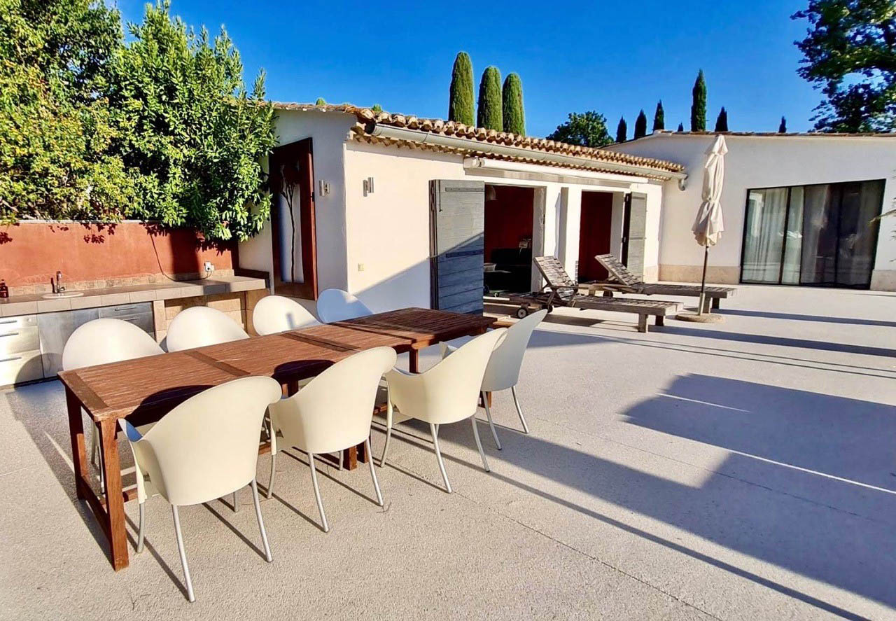 Terrasse repas et espaces extérieurs - maison Les Oliviers à Oppède Grande terrasse aménagée avec table de repas extérieure et bains de soleil devant la maison Les Oliviers à Oppède, en Luberon