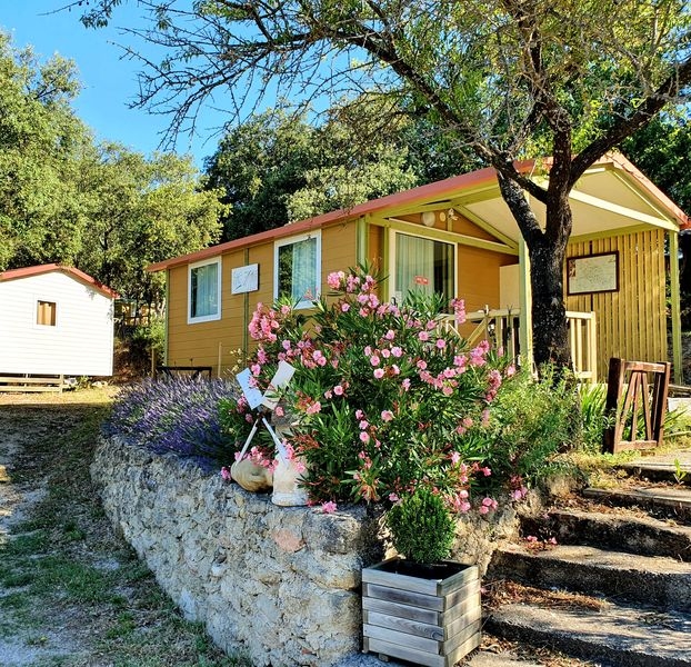 Chalet et nature au Camping Le Moulin à Vent Chalet coloré et accueillant au camping Le Moulin à Vent, entouré de verdure et de fleurs