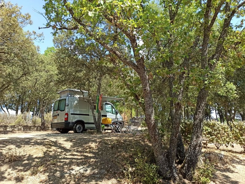 Emplacements spacieux et ombragés pour tentes, vans ou camping-cars, Camping Le Moulin à Vent Van aménagé installé sous les arbres sur un emplacement du Camping Le Moulin à Vent